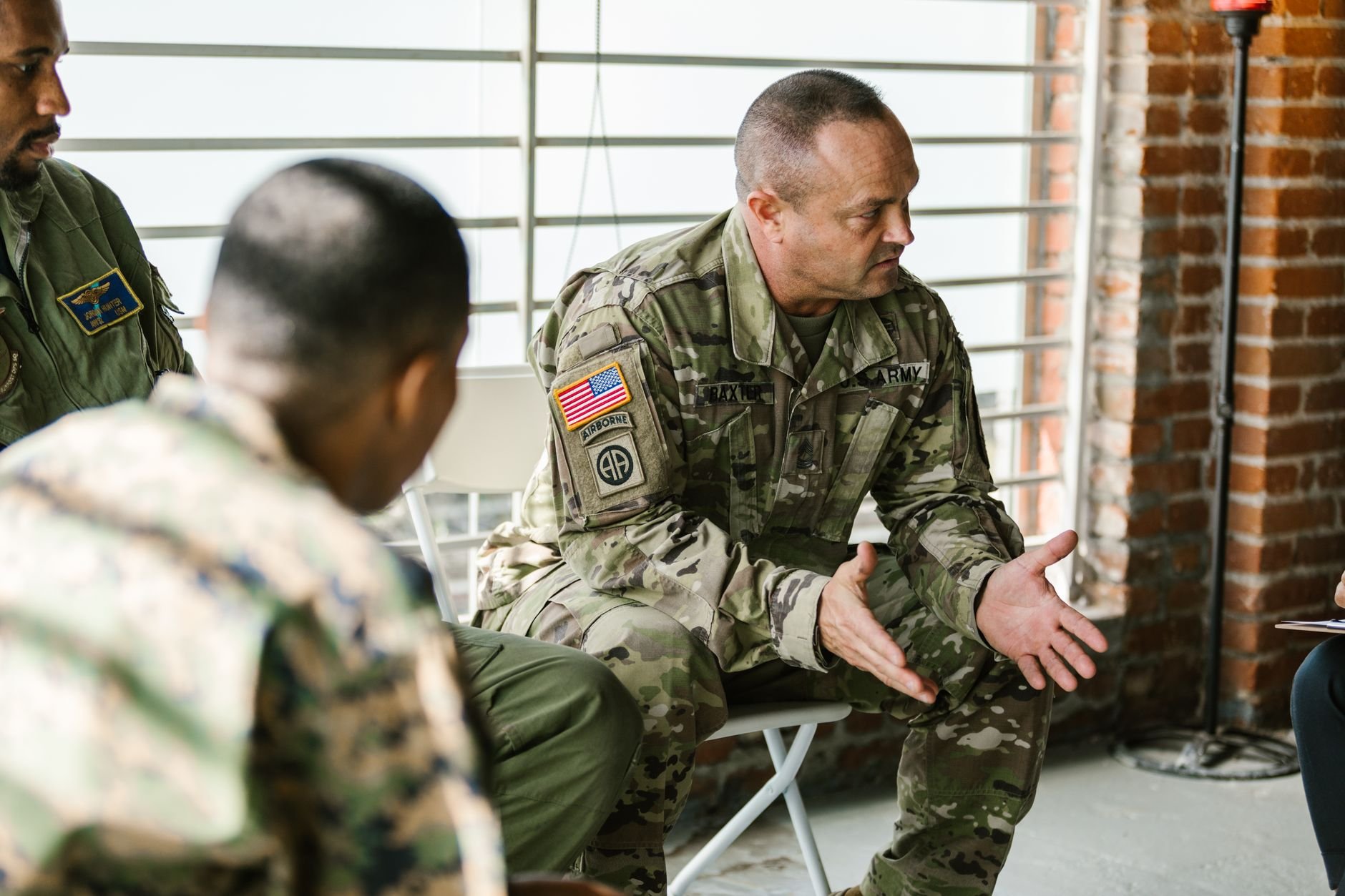 Military veterans engaging in a supportive group therapy session indoors.